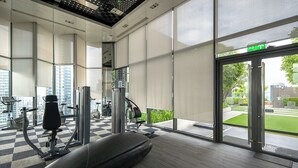 Ein Fitnessraum mit Trainingsgeräten, großen Fenstern und einem Schachbrettmuster-Boden.