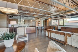 Un vaste espace de vie doté d’un plafond haut, d’un plancher en bois et d’un agencement varié comprenant des canapés et une table à manger.