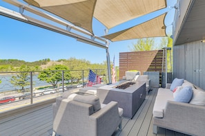 Une terrasse dotée de mobilier d’extérieur, d’un foyer et offrant une vue sur un plan d’eau.