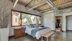 Un dormitorio moderno con una cama grande, suelo de madera y vistas al exterior.
