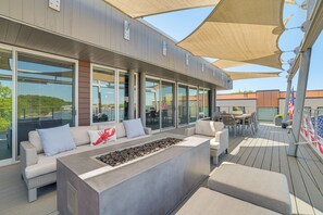 An outdoor deck with a seating area, a fire feature, and large windows. - Grand Haven Condo w/ Channel View & Dtwn Location (Grand Haven)