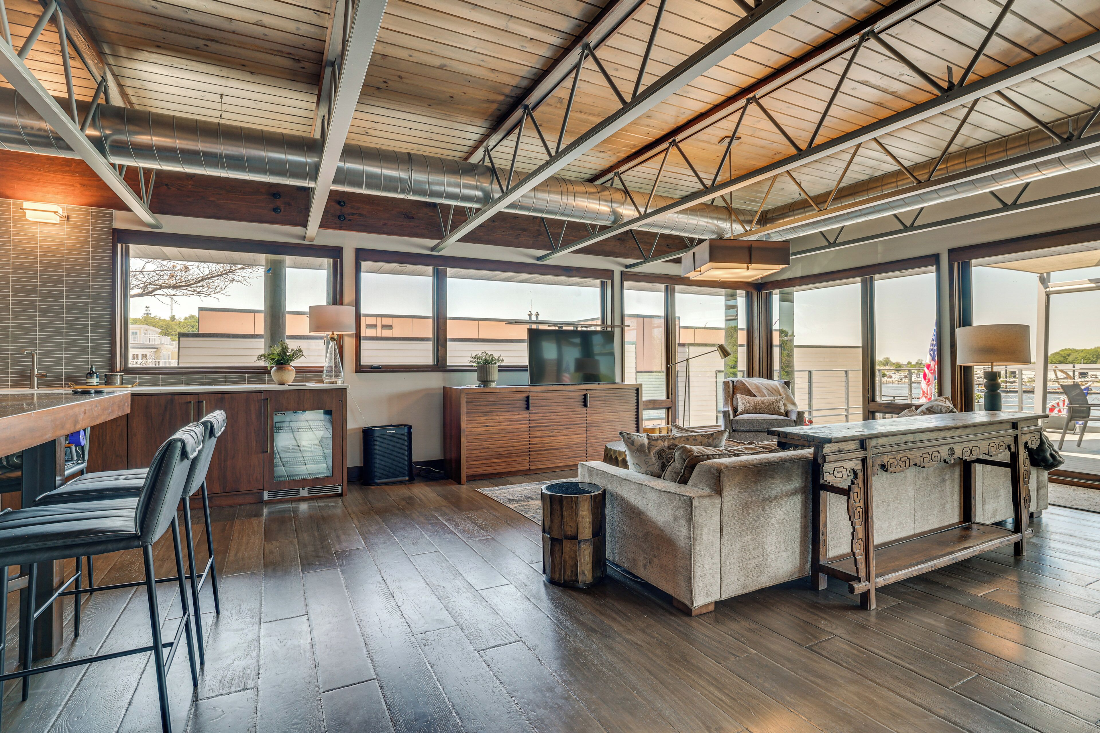 A spacious living area with a wooden floor, a sofa, a coffee table, and a kitchen area with a refrigerator, stove, and sink.