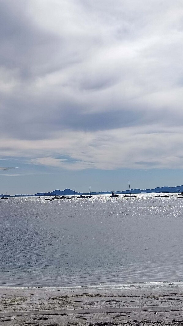 A beach with boats, calm water, and distant mountains. - Maison typique de San Pedro del Pinatar : Plages et toutes commodités à pied ! (San Pedro del Pinatar)