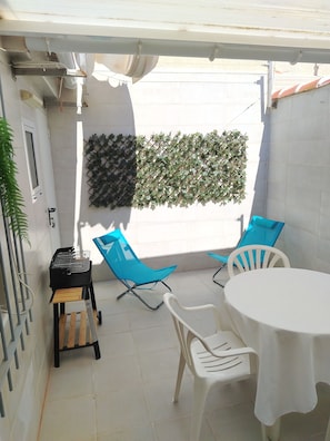 A patio with a grill, blue and white chairs, a table, and a decorative wall. - Maison typique de San Pedro del Pinatar : Plages et toutes commodités à pied ! (San Pedro del Pinatar)
