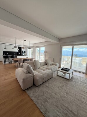 A spacious living area with a large sofa, a coffee table, and a dining area with chairs and a table. - Medinblu Apartments Via Cavour 12 (Reggio Calabria)
