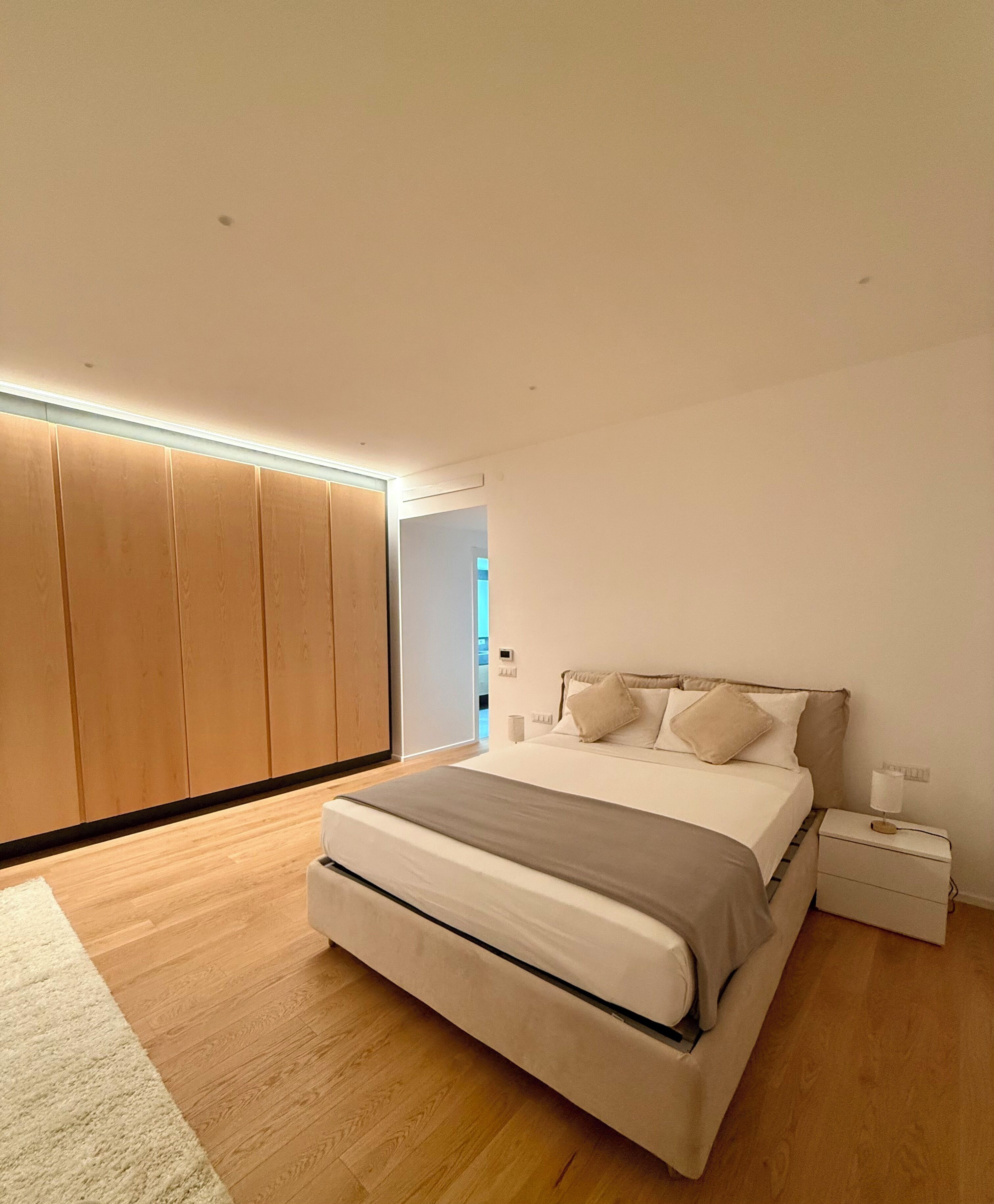 Ein modernes Schlafzimmer mit einem großen Bett, einem Holzschrank und einem Nachttisch.