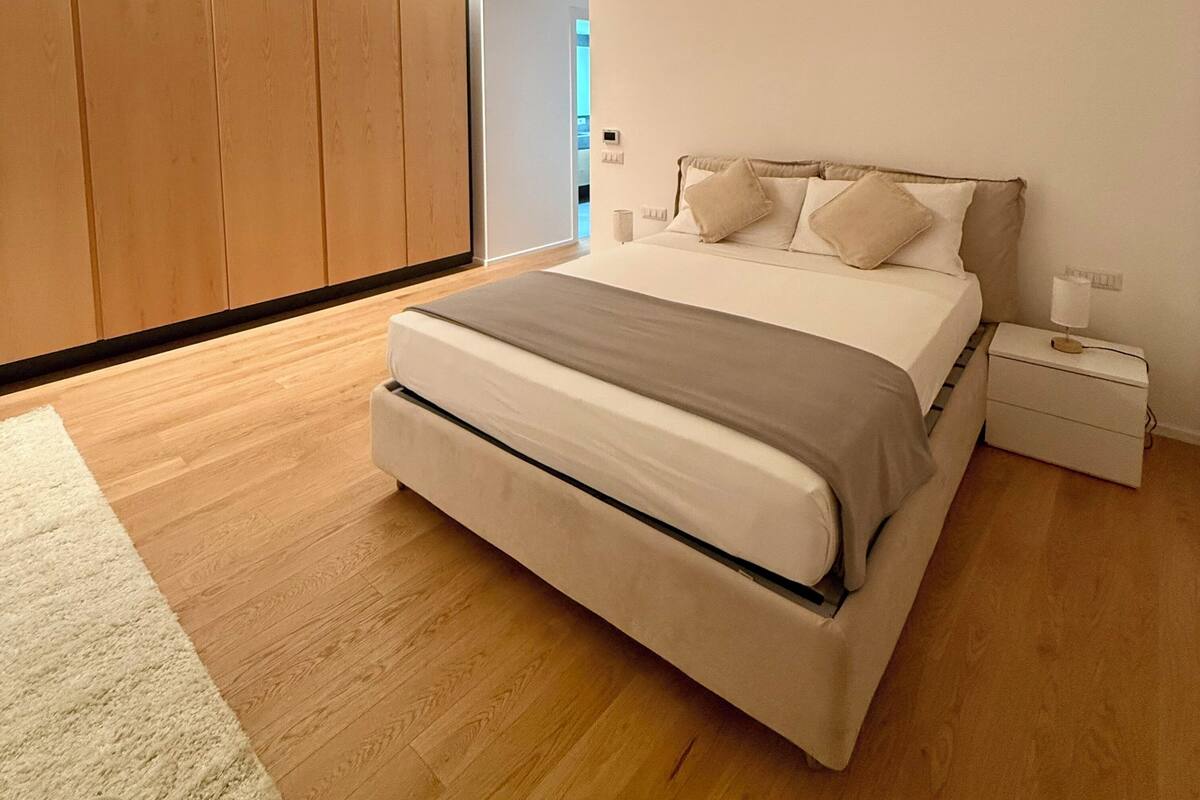 Une chambre à coucher moderne avec un grand lit, une armoire en bois et une table de chevet.