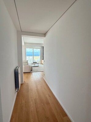 A hallway with wooden flooring, a radiator, and a view to a living area with a sofa and a table. - Medinblu Apartments Via Cavour 12 (Reggio Calabria)