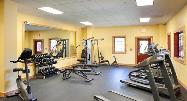 A gym with exercise equipment, a mirror, and a treadmill.