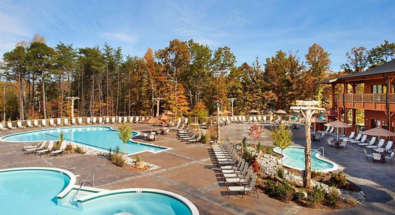 A resort with multiple swimming pools, lounge areas, and a wooden building.