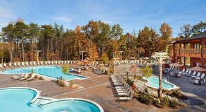 A resort with multiple swimming pools, lounge areas, and a wooden building.