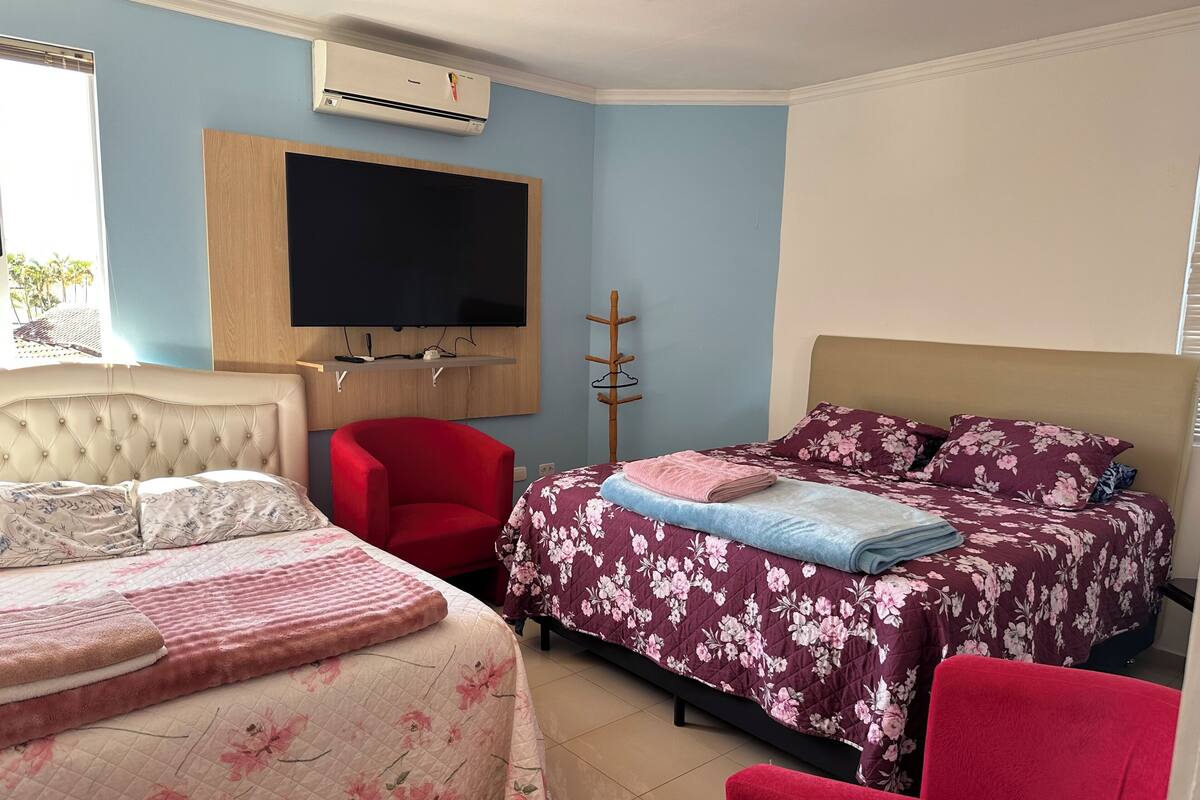 Ein Schlafzimmer mit zwei Betten, einem Fernseher und einer Klimaanlage.