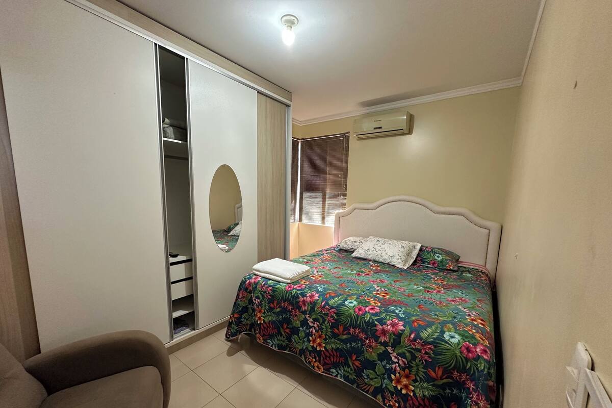 Ein Schlafzimmer mit Bett, Stuhl, Kleiderschrank und Klimaanlage.