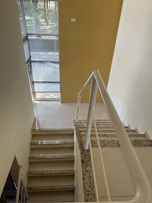 A staircase with a handrail, a window with blinds, and a thermostat on the wall. - Recanto Luna foz (Foz do Iguaçu)