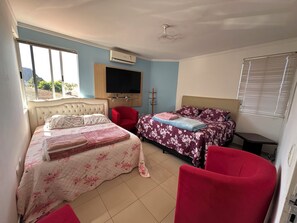 A bedroom with two beds, a TV, and a ceiling fan. - Recanto Luna foz (Foz do Iguaçu)