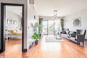 A modern living room with a sofa, armchairs, a coffee table, and a potted plant. - Cozy 1-bedroom hotel suite in terrific İstanbul with AC and gym (İstanbul)
