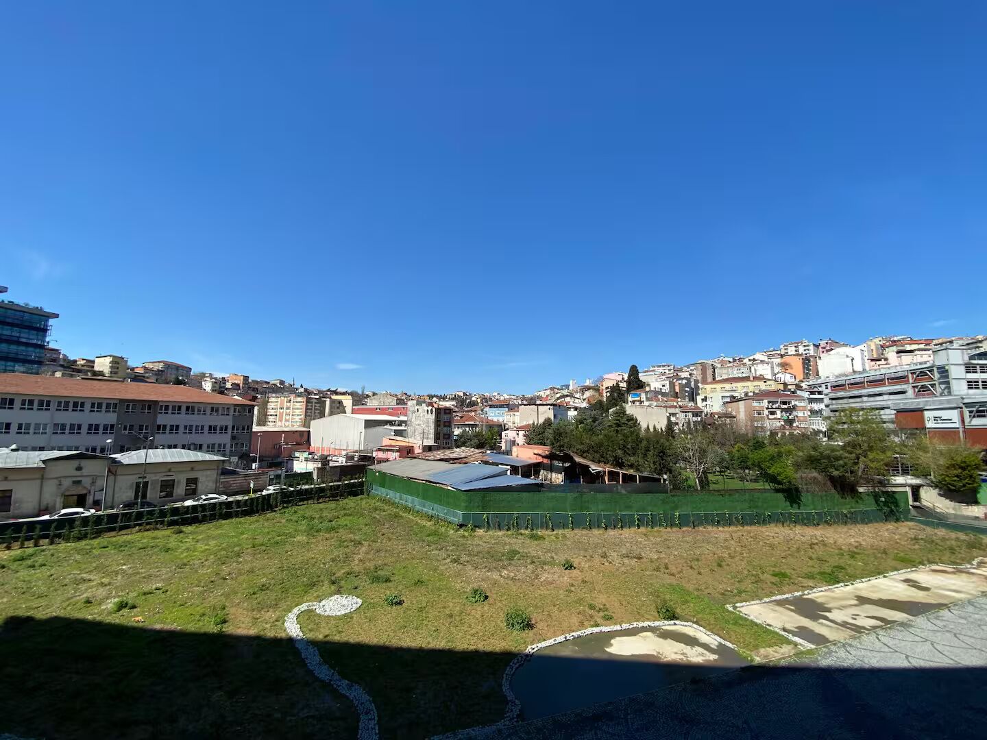 Paisaje urbano con edificios, un área cercada y cielo despejado.