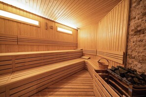 Eine Holzsauna mit Bänken, einer Steinwand und einem Holzboden.