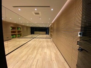 A spacious room with a wooden floor, mirrored walls, and shelves with green exercise balls. - Cozy 1-bedroom hotel suite in terrific İstanbul with AC and gym (İstanbul)