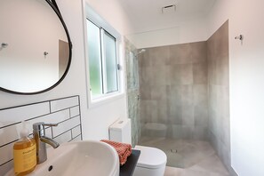 Een moderne badkamer met een groot wastafel, toilet en een douchecabine met glazen wanden.