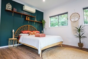 A bedroom with a bed, wooden headboard, bedside tables, a window, and a wall-mounted air conditioner. - The Poolhaus Retreat- Peaceful private guesthouse (Valdora)