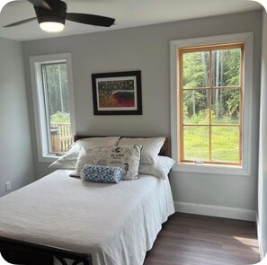 A bedroom with a bed, two windows, a ceiling fan, and a framed picture on the wall. - Get away from it all while you stay under the stars (Ocean City)