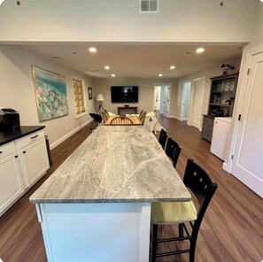 A spacious kitchen with a long island, white cabinetry, and a flat-screen TV. - Get away from it all while you stay under the stars (Ocean City)