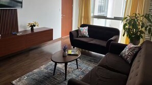 Una sala de estar moderna con sofá, mesa de centro, televisor y una planta en maceta.