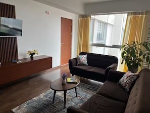 A modern living room with a sofa, coffee table, TV, and a potted plant. - Apartment with a view of the Magdalena del Mar, Lima (Lima)