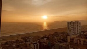 Un paisaje urbano costero con edificios cerca de la playa al atardecer.