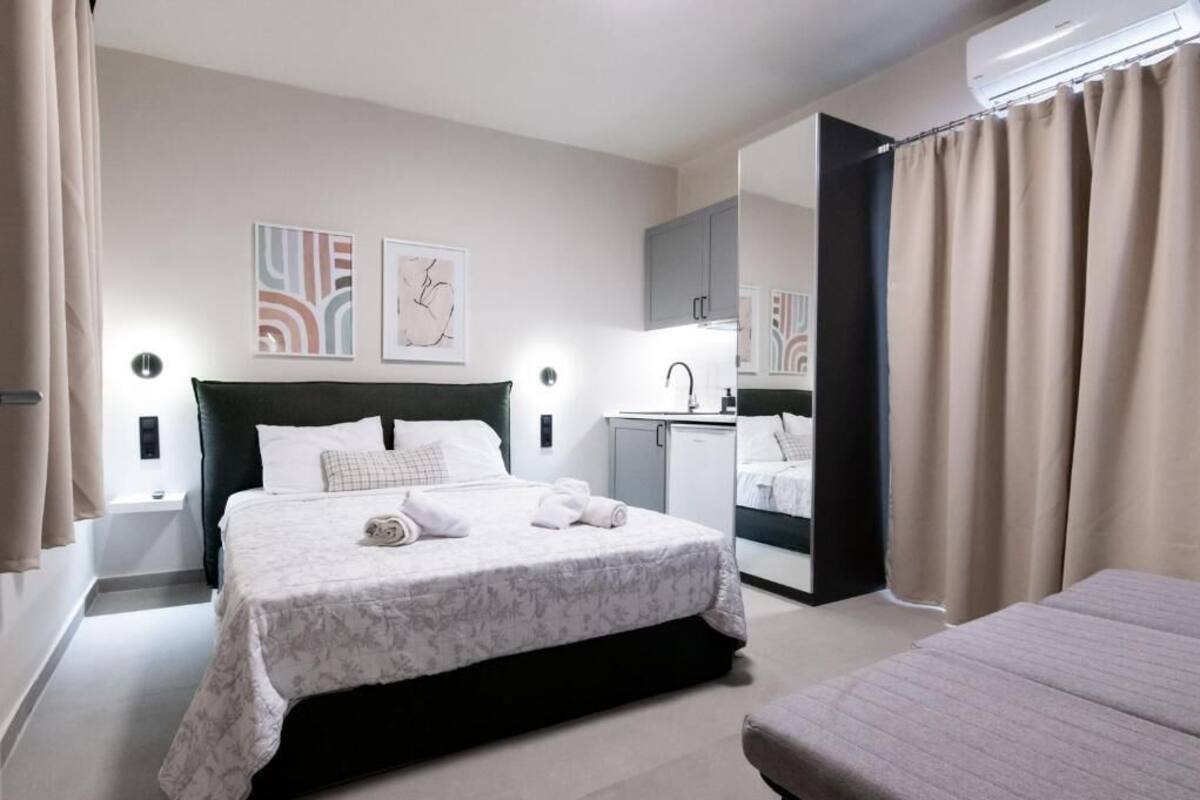 A hotel room with a bed, a small desk, a mirror, and a bathroom visible through an open door.
