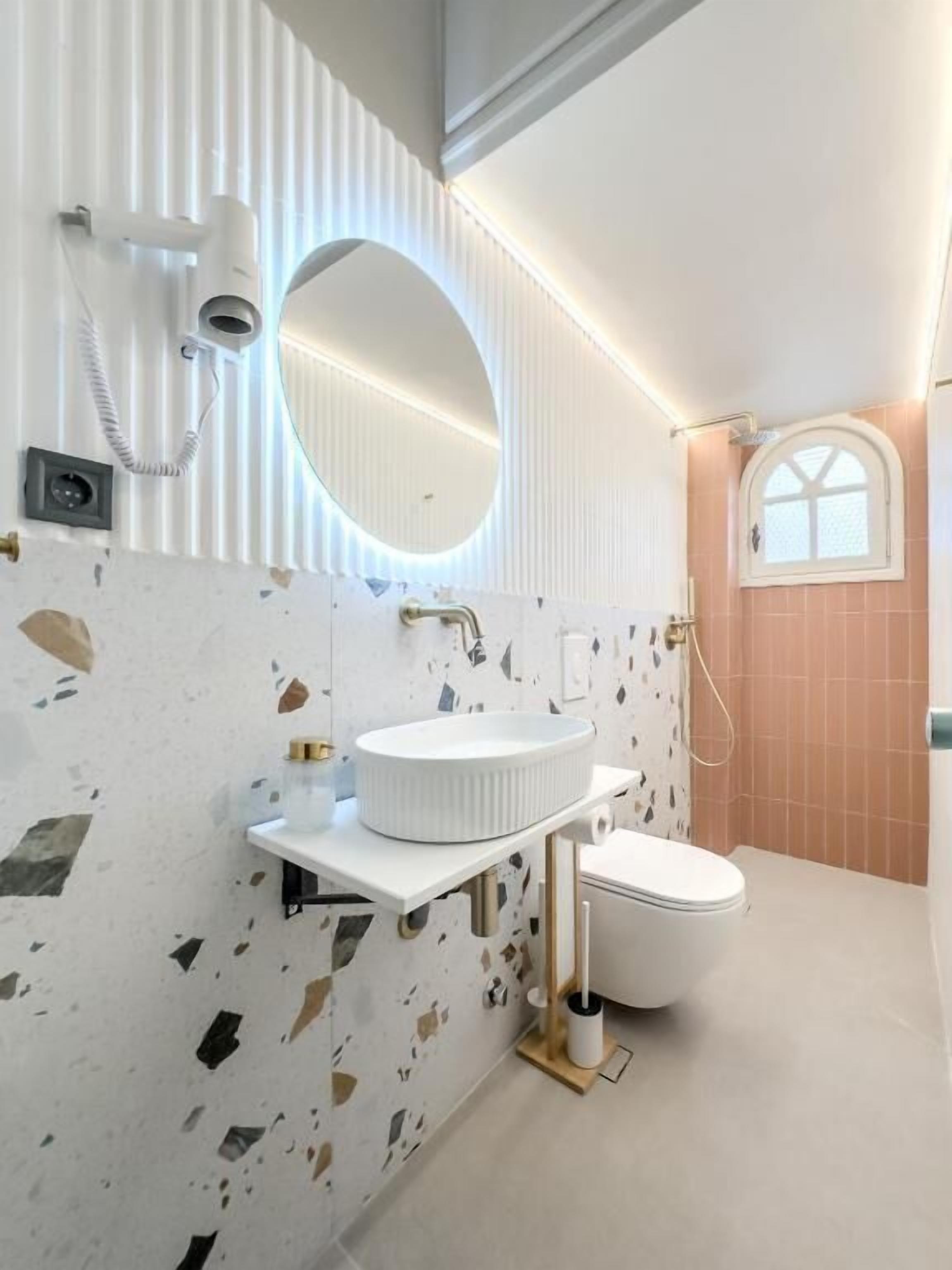 A bathroom with a white sink, a mirror, a toilet, and a shower.