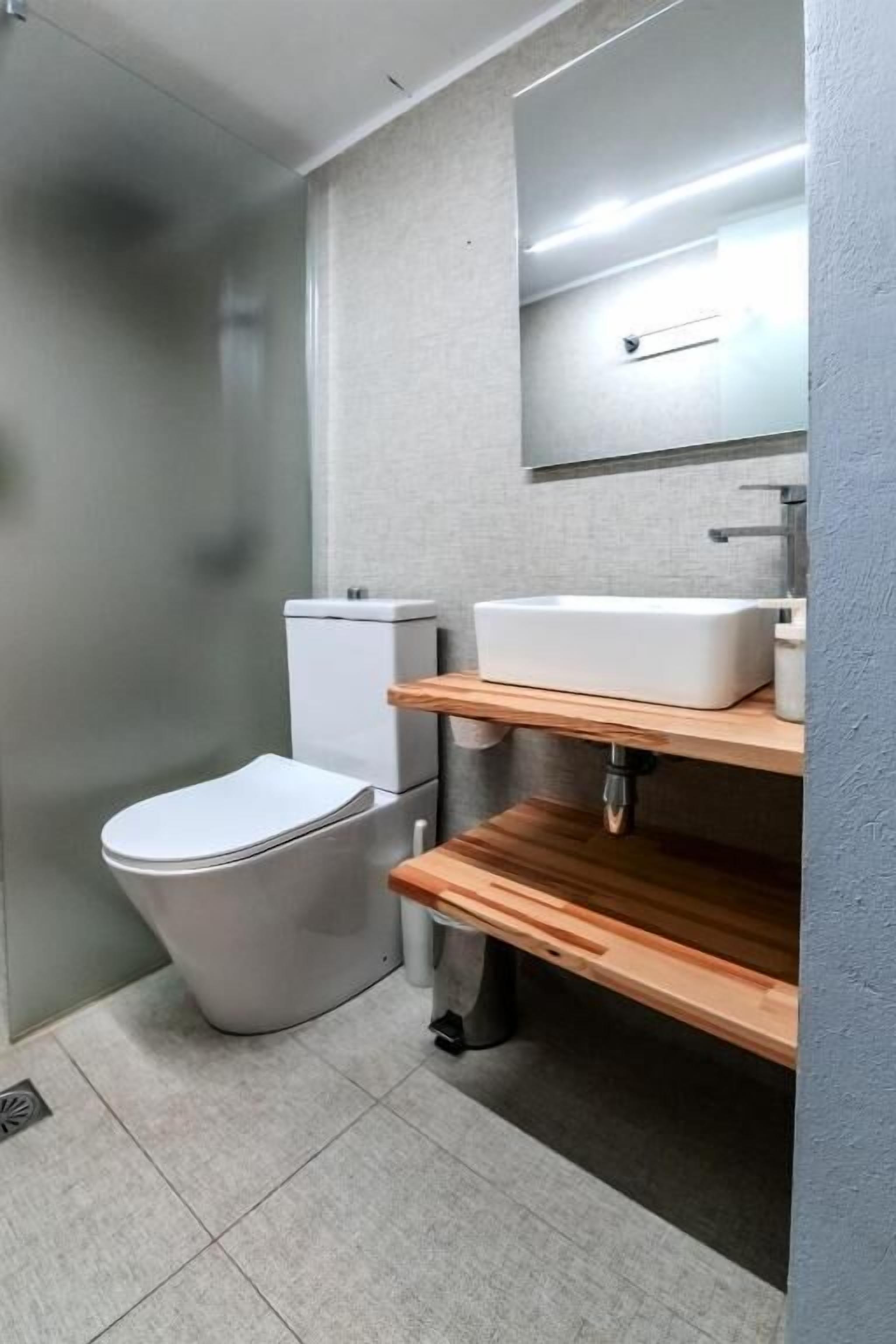 A bathroom with a toilet, a sink, and a mirror.