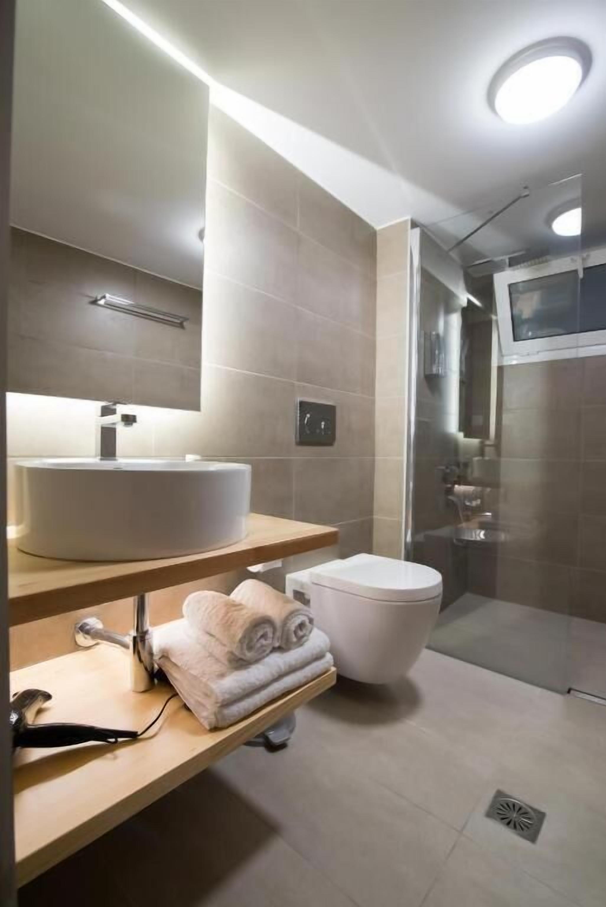 A modern bathroom with a large sink, toilet, and shower area.
