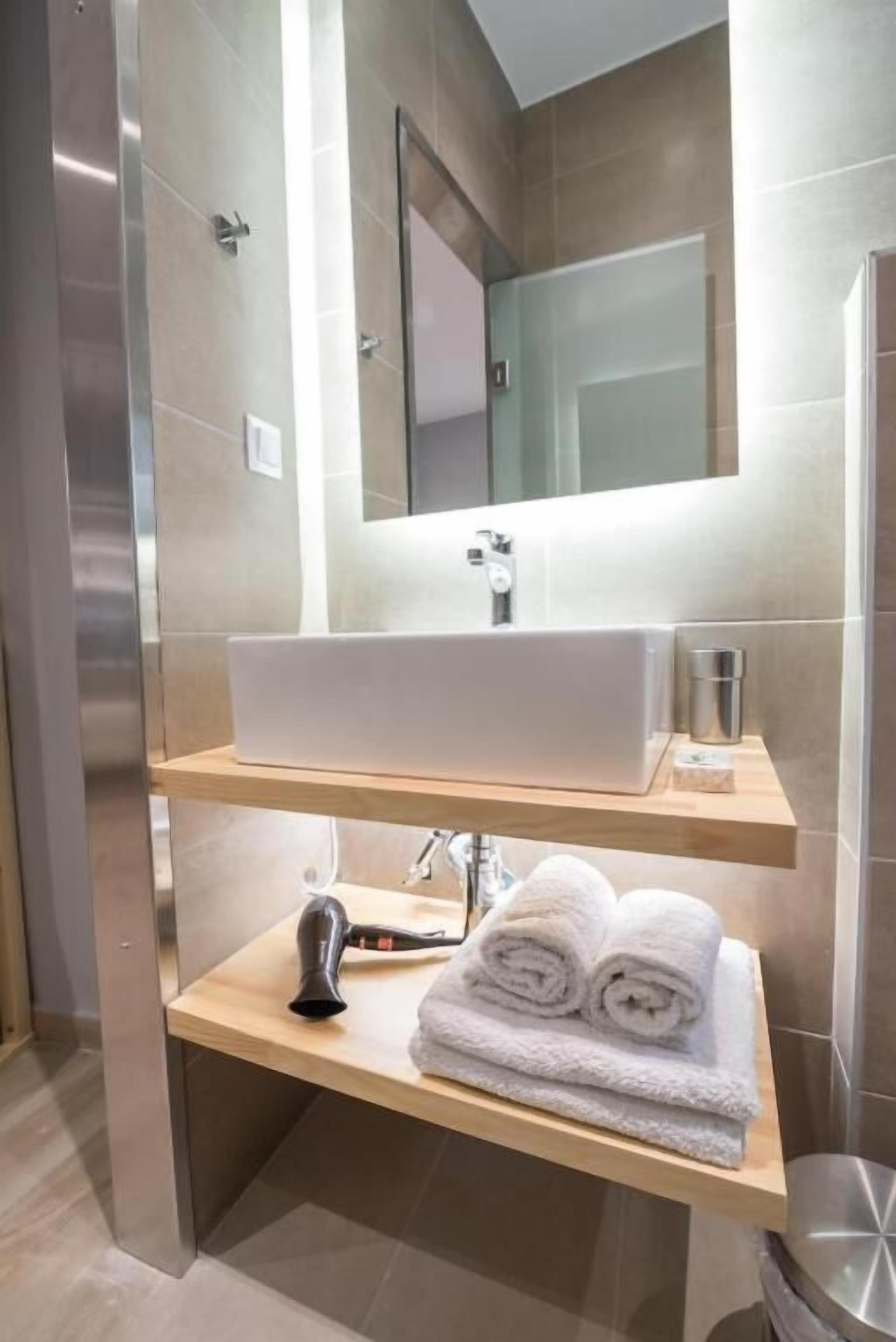 Une salle de bain moderne avec un grand miroir, un lavabo et un porte-serviettes.