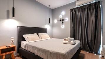 Un dormitorio moderno con una cama grande, mesitas de noche, una lámpara de pared y un ventanal con cortinas.