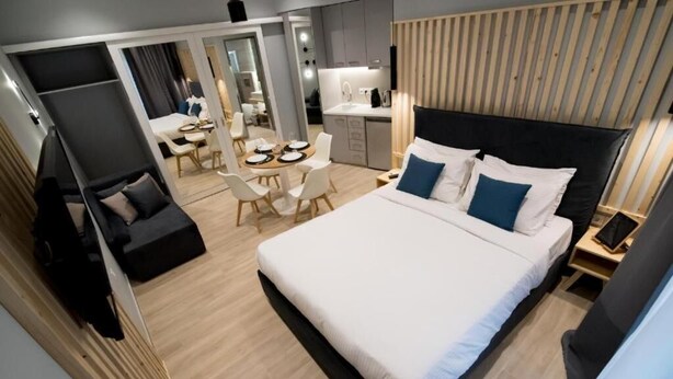 Una habitación de hotel moderna con una cama grande, un escritorio, un comedor y una kitchenette.