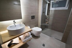 Un baño moderno con lavamanos, inodoro y cabina de ducha de vidrio.