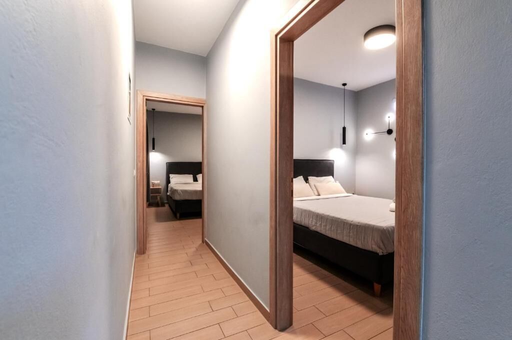 A hallway leading to a bedroom with a bed, bedside table, and a hanging light fixture.