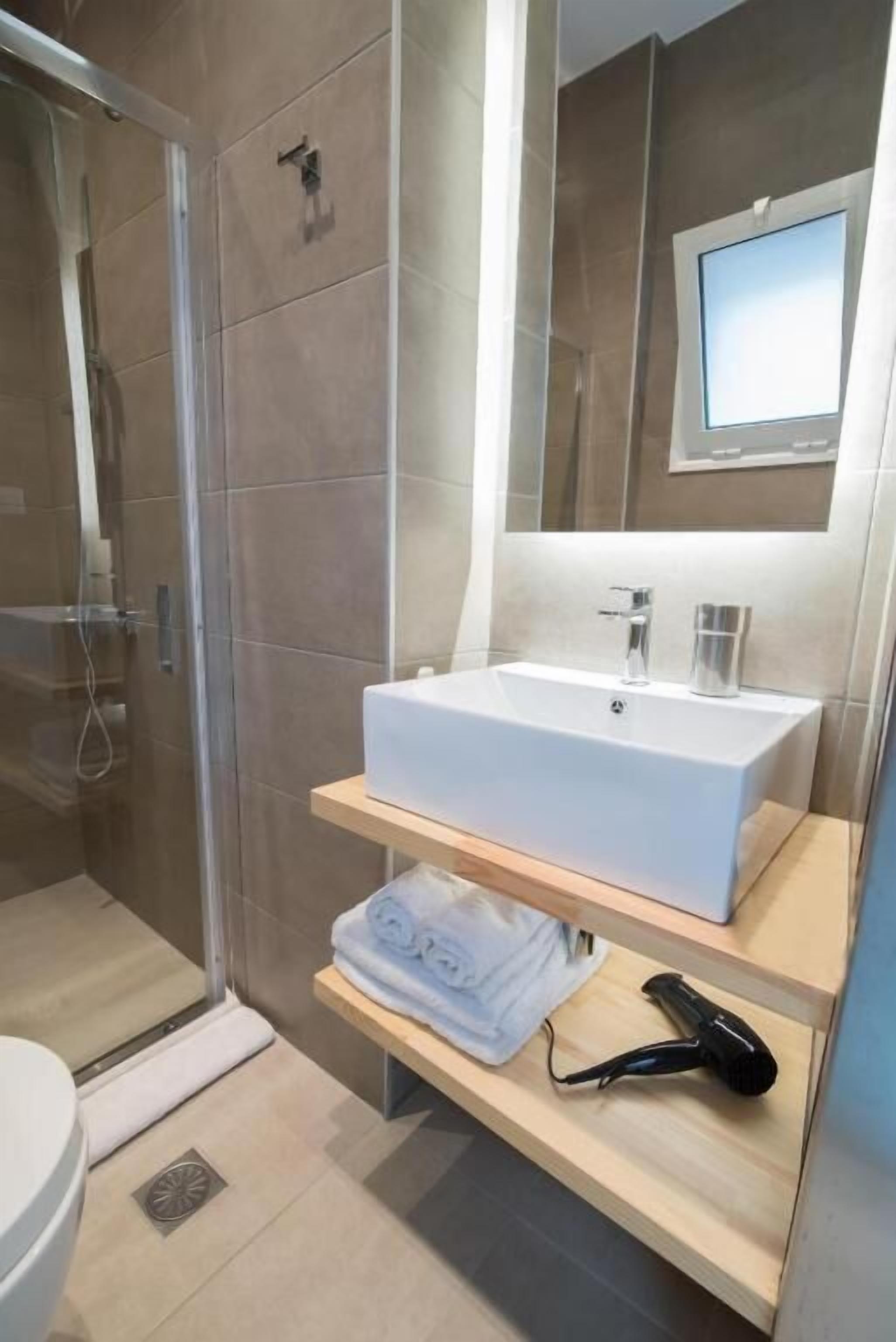 Un baño moderno con cabina de ducha de vidrio, un lavabo blanco y un espejo sobre él.