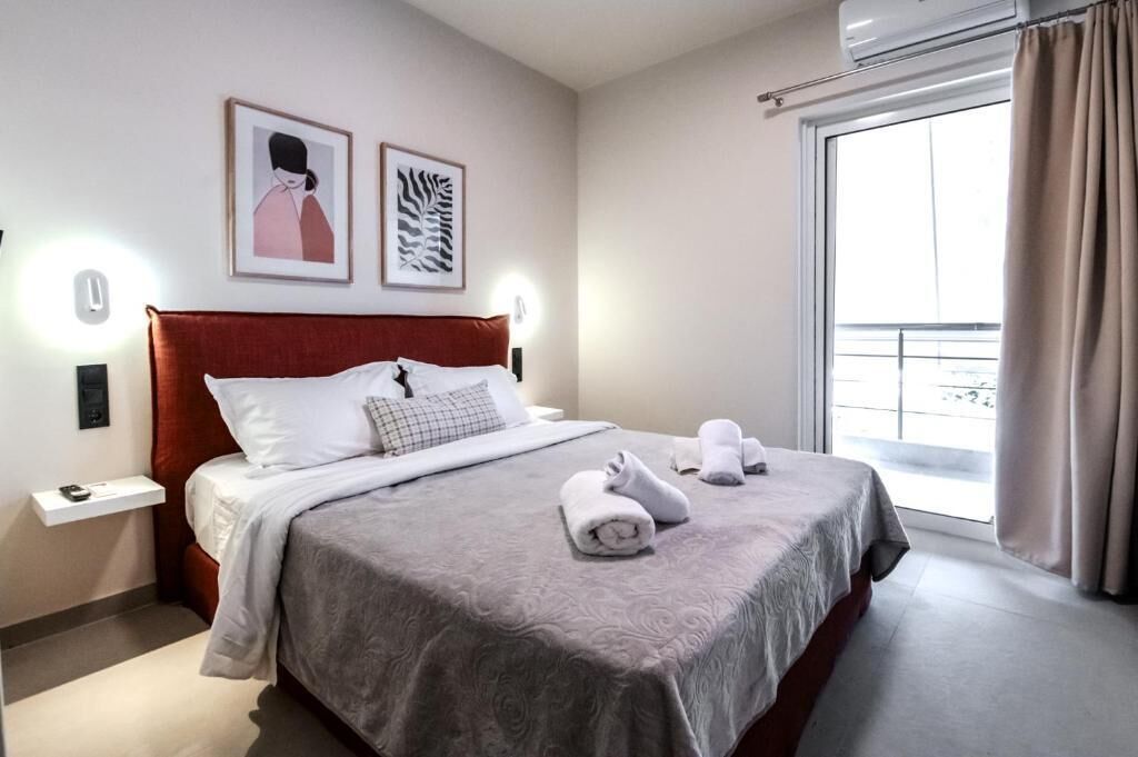 Habitación de hotel con cama, mesita de noche, aire acondicionado montado en la pared y ventana con cortinas.