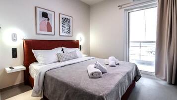 Habitación de hotel con cama, mesita de noche, aire acondicionado montado en la pared y ventana con cortinas.