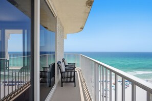 A balcony with a view of the ocean, a chair, and a table. - Shores of Panama #1301, 3BR/3BA, Wrap-around Balcony! (Panama City Beach)