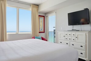 Ein Hotelzimmer mit Bett, Fernseher, Kommode und einem Fenster mit Vorhängen.