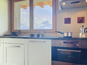 Eine Küche mit Fenster, Herd und Kaffeemaschine.