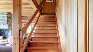 Una escalera de madera con barandilla que lleva a un muro de piedra.