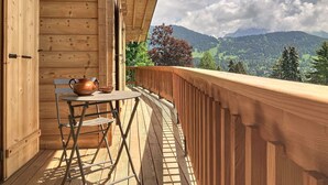 Un balcón de madera con una mesa y sillas, con vistas a un paisaje montañoso.