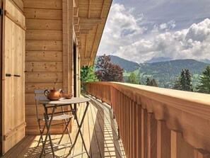 Ein Holzbalkon mit Tisch und Stühlen mit Blick auf eine gebirgige Landschaft.