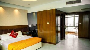 Ein Hotelzimmer mit einem Bett, einem Holzschrank, einem Schreibtisch mit Stuhl und Blick ins Freie.