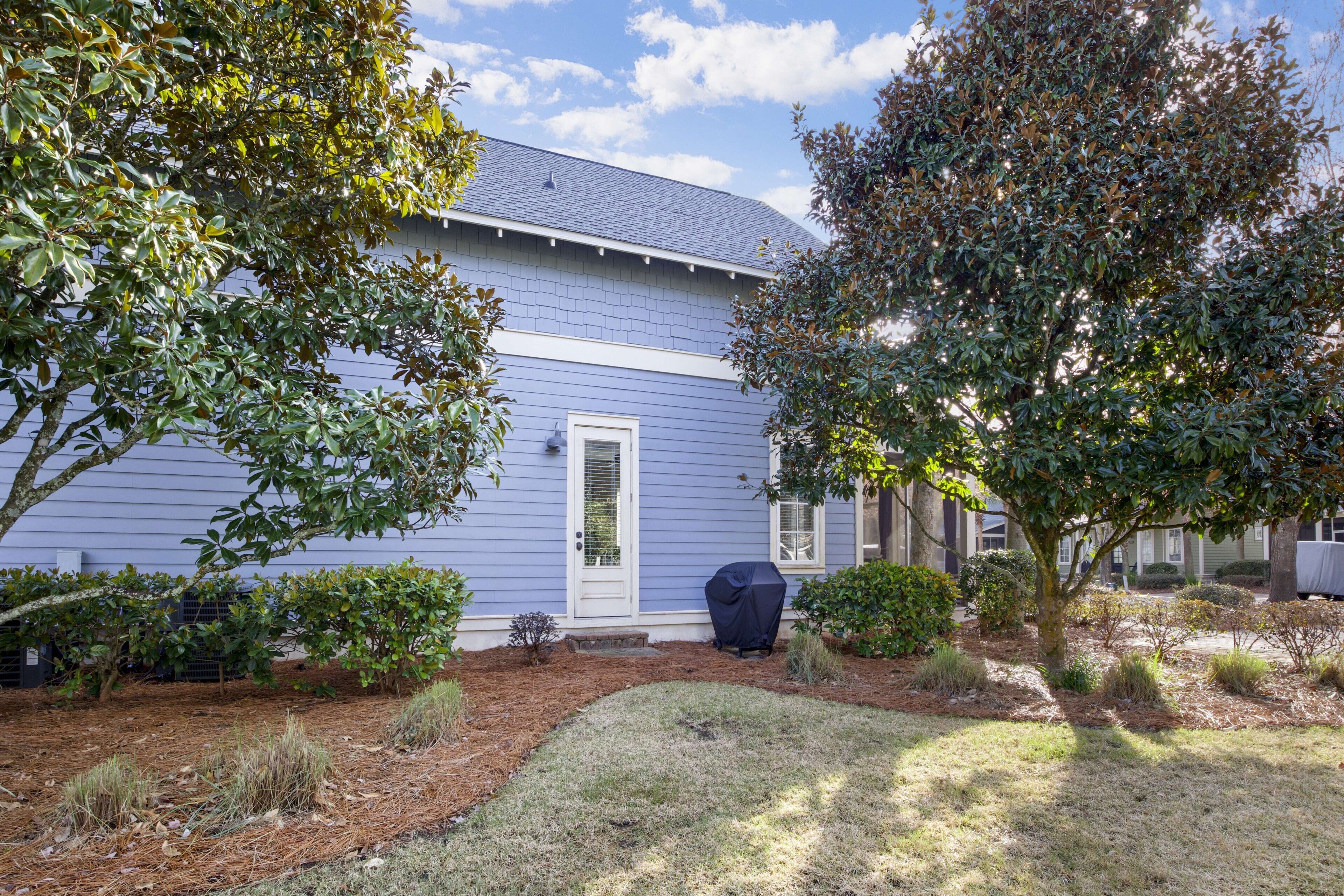 A house with a blue exterior, a front door, and a covered grill.